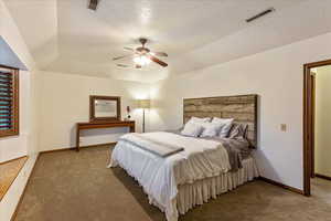 Bedroom with carpet floors, a textured ceiling, a ceiling fan, and a raised ceiling