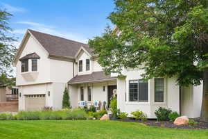 View of front of property with brick siding, a front lawn, roof with shingles, and an attached garage