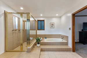 Bathroom featuring a garden tub, a shower stall, light tile patterned floors, and recessed lighting