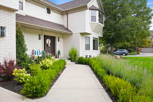 Doorway to property with roof with shingles, stucco siding, and brick siding