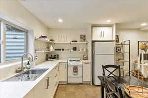 Kitchen featuring open shelves, white appliances, white cabinets, recessed lighting, and light stone countertops