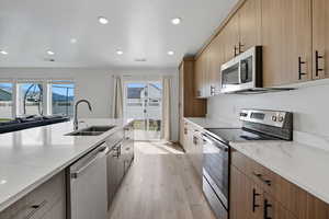 Kitchen featuring stainless steel appliances, light stone countertops, modern cabinets, light wood-style floors, and recessed lighting