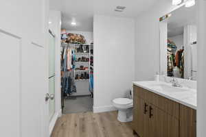 Full bathroom featuring vanity, light wood-style flooring, a spacious closet, and a shower stall