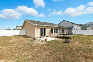 Rear view of property with a patio area, a trampoline, a fenced backyard, and a fire pit