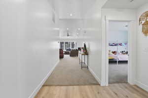Hallway with light wood finished floors, recessed lighting, and light colored carpet