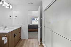 Bathroom featuring light wood-type flooring, vanity, a shower stall, and connected bathroom