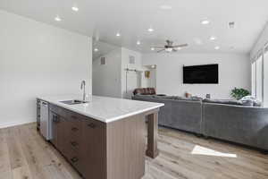 Kitchen featuring a barn door, a ceiling fan, light stone counters, a kitchen island with sink, and open floor plan