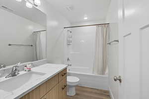 Bathroom featuring shower / bathtub combination with curtain, vanity, and light wood-style flooring