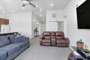 Living area with a barn door, light colored carpet, ceiling fan, and recessed lighting