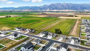 Overview of rural landscape featuring a mountainous background, nearby suburban area, and large plots for crops