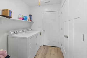 Laundry room with light wood-style floors and independent washer and dryer