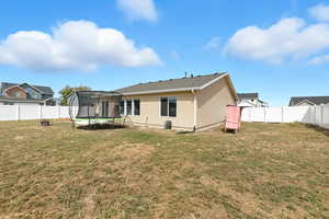 Rear view of property featuring a trampoline and a fenced backyard