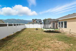 Fenced backyard featuring a trampoline and a mountain view