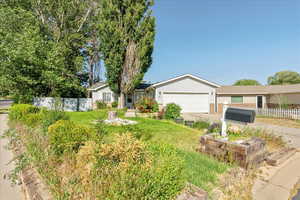 Single story home with concrete driveway, a garage, a vegetable garden, and brick siding