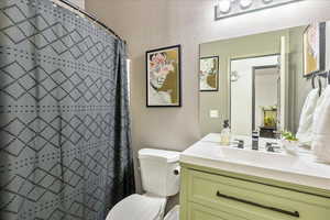 Bathroom with a textured wall, vanity, and a shower stall