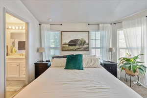 Bedroom featuring connected bathroom and light carpet