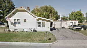 View of front of property with a chimney, a front yard, and asphalt driveway