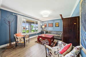 Living area with ornamental molding, wood finished floors, and a baseboard radiator