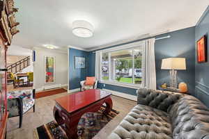 Living area featuring crown molding, light wood finished floors, baseboard heating, stairs, and a textured ceiling