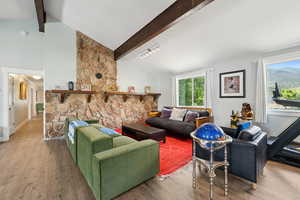 Living area with beamed ceiling, wood finished floors, and high vaulted ceiling