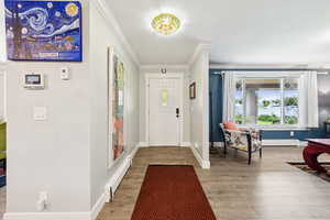 Entryway with crown molding, light wood finished floors, and a baseboard radiator