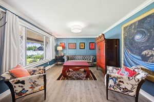 Living area featuring crown molding, wood finished floors, and a baseboard heating unit