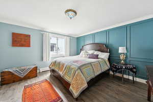 Bedroom featuring ornamental molding, a baseboard heating unit, and dark wood-type flooring
