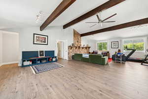 Living area with light wood finished floors, a ceiling fan, high vaulted ceiling, and beamed ceiling