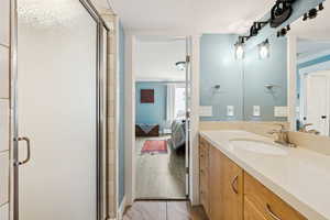Bathroom featuring a stall shower, vanity, ensuite bathroom, and light wood-style flooring