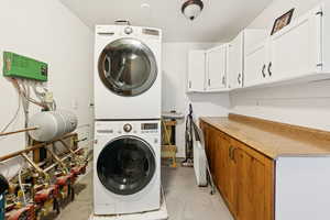 Washroom featuring stacked washer / drying machine and cabinet space