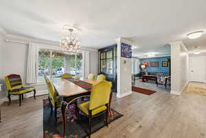 Dining room with wood finished floors, crown molding, a chandelier, and a baseboard heating unit