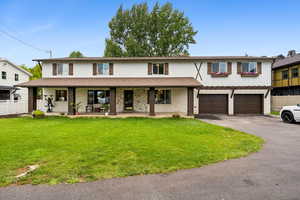 Traditional home with driveway, brick siding, a porch, and an attached garage