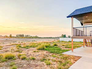 Yard at dusk with stairs, a view of countryside, and a patio area