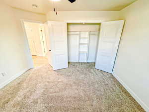 Unfurnished bedroom featuring light colored carpet, a closet, and a ceiling fan