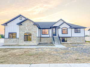 Modern farmhouse style home featuring board and batten siding, stone siding, and a shingled roof