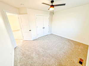 Unfurnished bedroom featuring light carpet, a closet, and a ceiling fan