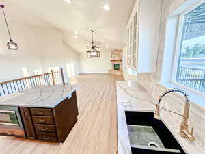 Kitchen featuring light stone countertops, light wood finished floors, hanging light fixtures, dark brown cabinets, and recessed lighting