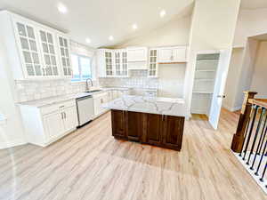 Kitchen with glass insert cabinets, tasteful backsplash, recessed lighting, a center island, and vaulted ceiling