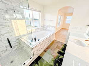 Full bath with a garden tub, a marble finish shower, vanity, and a water view