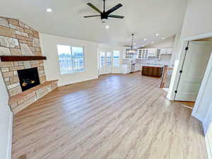 Unfurnished living room with recessed lighting, a fireplace, vaulted ceiling, light wood-style flooring, and ceiling fan