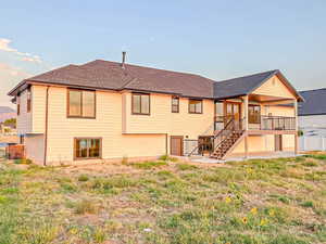 Rear view of property featuring stairs and roof with shingles