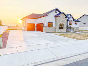 View of front of home with stone siding, board and batten siding, and concrete driveway