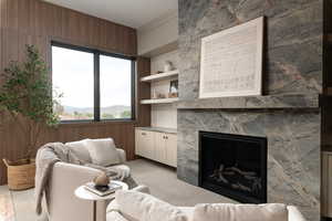 Living room with a premium fireplace, light carpet, and built in shelves