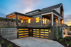 Back of property at dusk featuring a shingled roof, concrete driveway, and a garage
