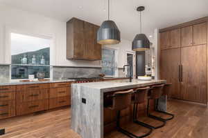 Kitchen featuring brown cabinetry, a breakfast bar, light wood-type flooring, and a center island with sink