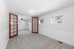 Spare room featuring carpet, french doors, and ceiling fan