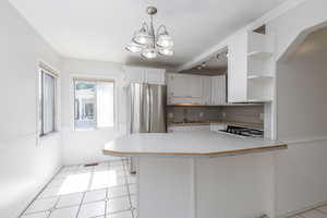 Kitchen with open shelves, white cabinetry, light tile patterned floors, light countertops, and decorative light fixtures