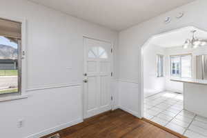 Entryway with dark wood-style floors and a chandelier