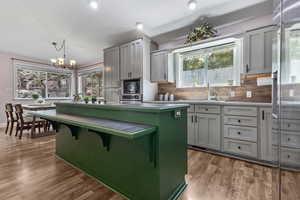 Kitchen featuring decorative light fixtures, tasteful backsplash, stainless steel countertops, light wood-style flooring, and recessed lighting