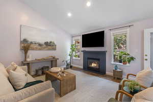 Living room featuring vaulted ceiling, wood finished floors, recessed lighting, and a tile fireplace